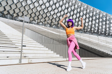 Carefree active woman dancer wearing colorful sportswear having fun on the street