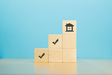 Wooden block pyramid with house and marks icon on wooden table and blue background. Construction, engineering concept.