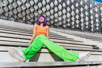 Carefree woman wearing colorful sportswear on the street during summer day