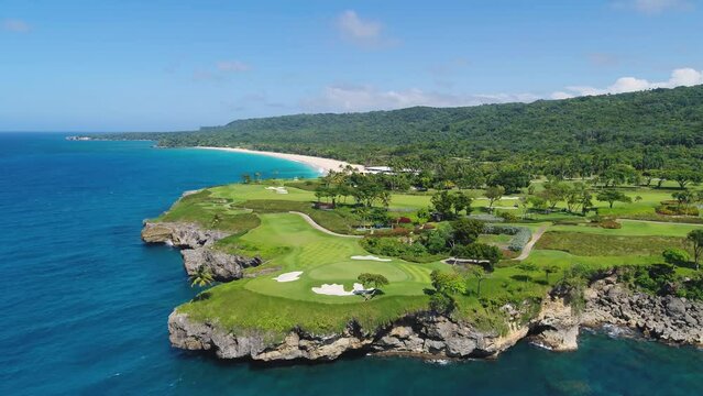 Golf park on a tropical peninsula, top view. Green fields against the background of the blue sea. Sea coast on a summer sunny day. Outdoor sports. Travel and recreation on the sea coast. Seascape.