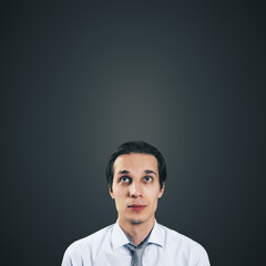 Man looking up in white shirt and tie isolated on blank dark grey background with empty space for your text or logo, mockup. Thinking and brainstorming concept, close up
