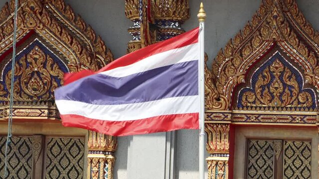 The Thai national flag flutters in front of the entrance to a Buddhist temple