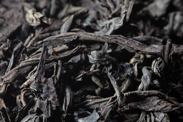 Dried black tea leaves as background.