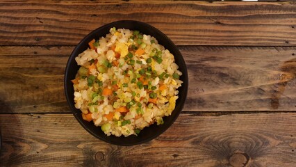 Healthy fried rice mixed with vegetables, eggs, homemade on a wooden table. rice on a wooden table.