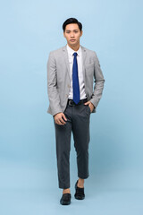 Asian man wearing business suit with modern ankle pants walking in light blue studio isolated background