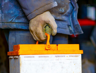 A man carries an old car battery in his hand for recycling and disposal. Selective focus. The concept of toxic waste.