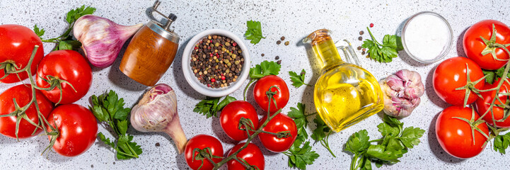 Cooking ingredients background. Spices, black pepper, garlic, onion, greens, tomatoes. olive oil on white stone concrete table top view copy space. Preparation healthy food background.