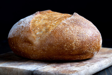 a whole loaf of bread on a cutting wooden board