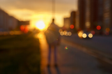 Out of focus sunset background of the city, embankment street, cars and people on the city street