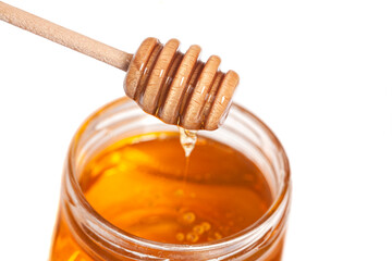 Honey dripping from honey dipper in glass jar. Healthy food concept