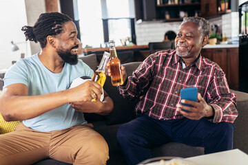 Man with senior father watch football together with beer celebrating
