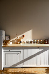 A vertical photo of a wood-style kitchen with sunlight in the morning.