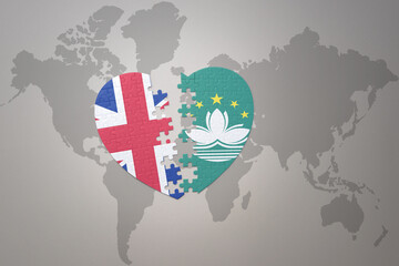 puzzle heart with the national flag of Macau and great britain on a world map background. Concept.