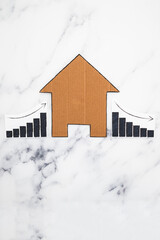 mortgages rentals and property prices increasing and decreasing, house icon made of cardboard with graph showing stats going up and down