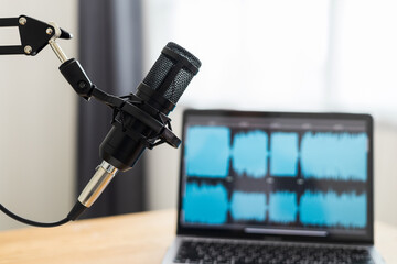 Condenser microphone in recording home studio. Content creator working with laptop host streaming radio podcast interview conversation at home broadcast studio recording waveform voice over radio
