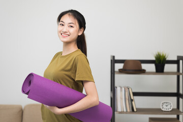 Fototapeta na wymiar Young beautiful asian woman standing pose smiling to camera holding yoga mat. Cheerfully sporty female workout and exercise wearing sport wear. Charming woman relax after fitness training.