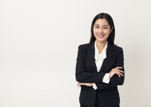 Young asian business woman smiling to camera standing pose on isolated white background. Female around 25 in suit portrait shot in studio.