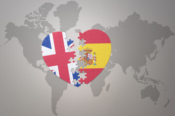 puzzle heart with the national flag of spain and great britain on a world map background. Concept. - obrazy, fototapety, plakaty