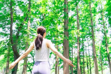 Naklejka premium 森林の中で深呼吸する女性の後ろ姿