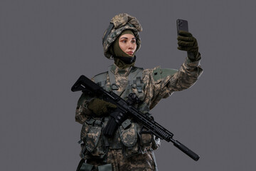 Shot of militant woman dressed in protective suit making selfie against grey background.