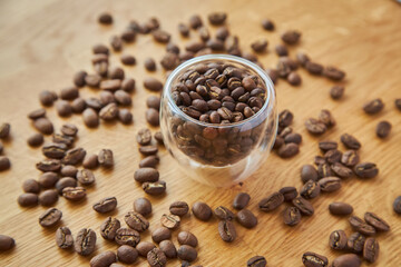 Coffee beans in a transparent bowl over a wood tablet with copy space.