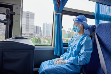 Female medical worker in medical mask and protective shield on her head makes her way to the hospital during the COVID-19 pandemic.