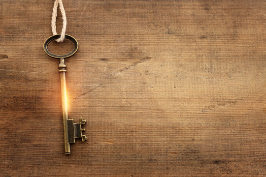 Top view image of old key with golden light over wooden background