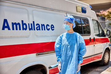 Paramedic with a protective workwear, ambulance car in the background. © Dusan