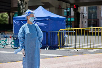 Medical worker in protective suits and surgical face masks on the street. City blockade.