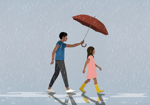 Father holding umbrella over daughter walking in rain
