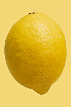 Close up dimples on vibrant, whole yellow lemon

