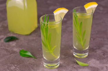 Italian lemon liquor limoncello in glasses on a gray background.
