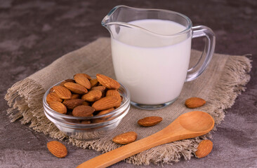 Almond milk in an almond decanter on a wooden tray.