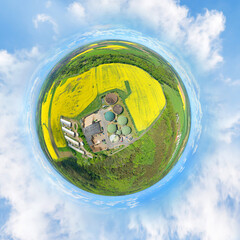 Biogas plant and farm in blooming rapeseed fields. Renewable energy from biomass. Aerial view to...