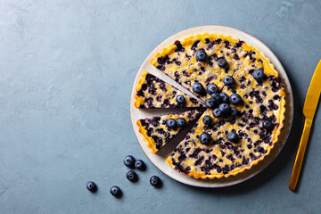 Blueberry tart with vanilla custard cream. Blue background. Copy space. Top view. - obrazy, fototapety, plakaty