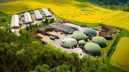 Biogas plant and farm in blooming rapeseed fields. Renewable energy from biomass. Aerial view to modern agriculture in Czech Republic and European Union.	 - obrazy, fototapety, plakaty