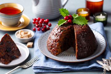 Christmas pudding, fruit cake with cup of tea. Traditional festive dessert. Grey background. Close up.