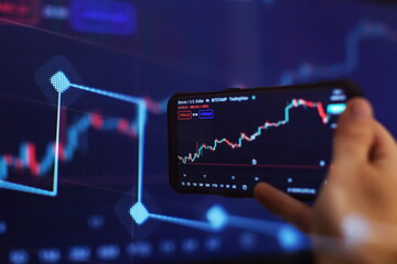 Trader investor broker holding finger using cell phone app executing financial stock trade market...
