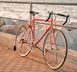 Fototapeta na wymiar Orange vintage road bicycle. Closeup of a bike on the seaside during a summer evening. Old cycle restored.