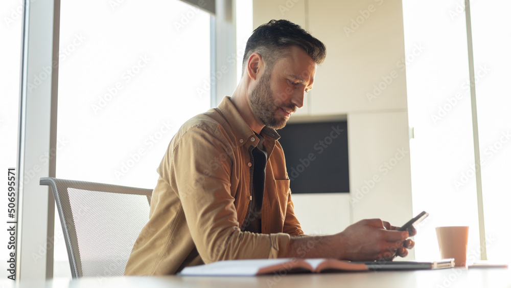Poster entrepreneur man using cellphone with business application working in office