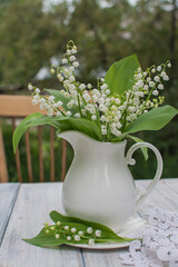 Bouquet of lilies of the valley in an antique white ceramic jug.