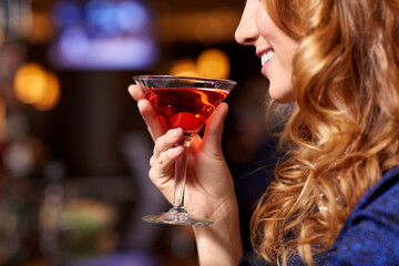 leisure and people concept - close up of smiling woman drinking red cocktail at night club