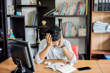 Portrait of an upset businessman at desk in office. Businessman being depressed by working in office. Young stressed business man feeling strain in eyes after working for long hours on computer.