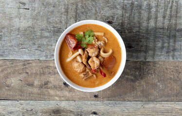 Thai spicy soup Tom Yam with seafood on a wooden background, top view. Traditional Asian food.