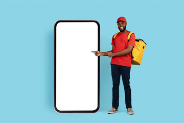 Order Here. Happy Black Delivery Guy Pointing At Big Blank Smartphone Screen