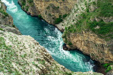top view of a fast mountain river flowing at the bottom of a deep canyon