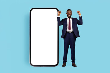 Overjoyed African American Businessman Standing Near Big Blank Smartphone And Celebrating Success