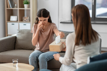 Fototapeta na wymiar psychology, mental health and people concept - crying woman patient taking paper tissue from psychologist at psychotherapy session