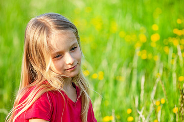 beautiful little Ukrainian girl with long white hair against the background of field grass.