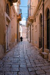 Fototapeta na wymiar Scicli alley with elderly lady walking